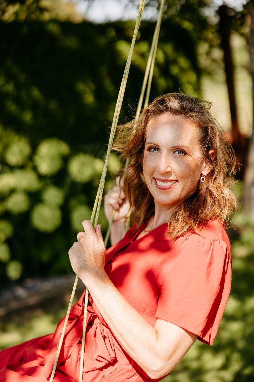 Annick lächelt auf einer Schaukel im Garten