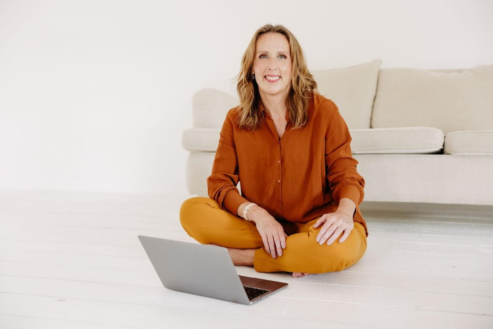 Annick Weikert sitzt lächelnd mit dem Laptop auf dem Boden