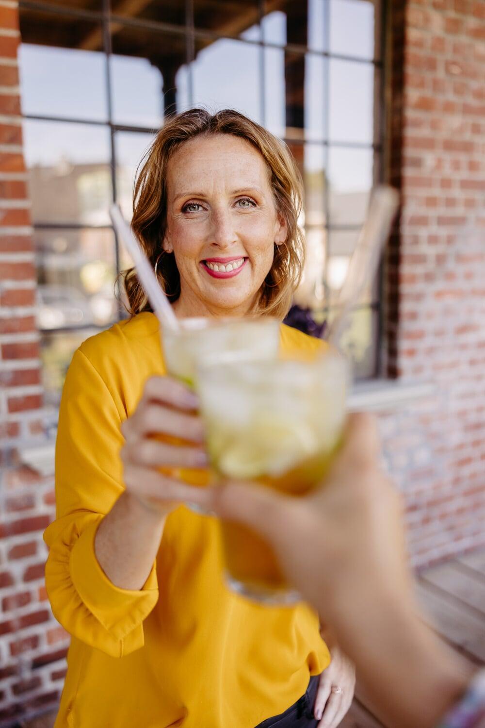 Annick stößt lachend mit einem Glas an
